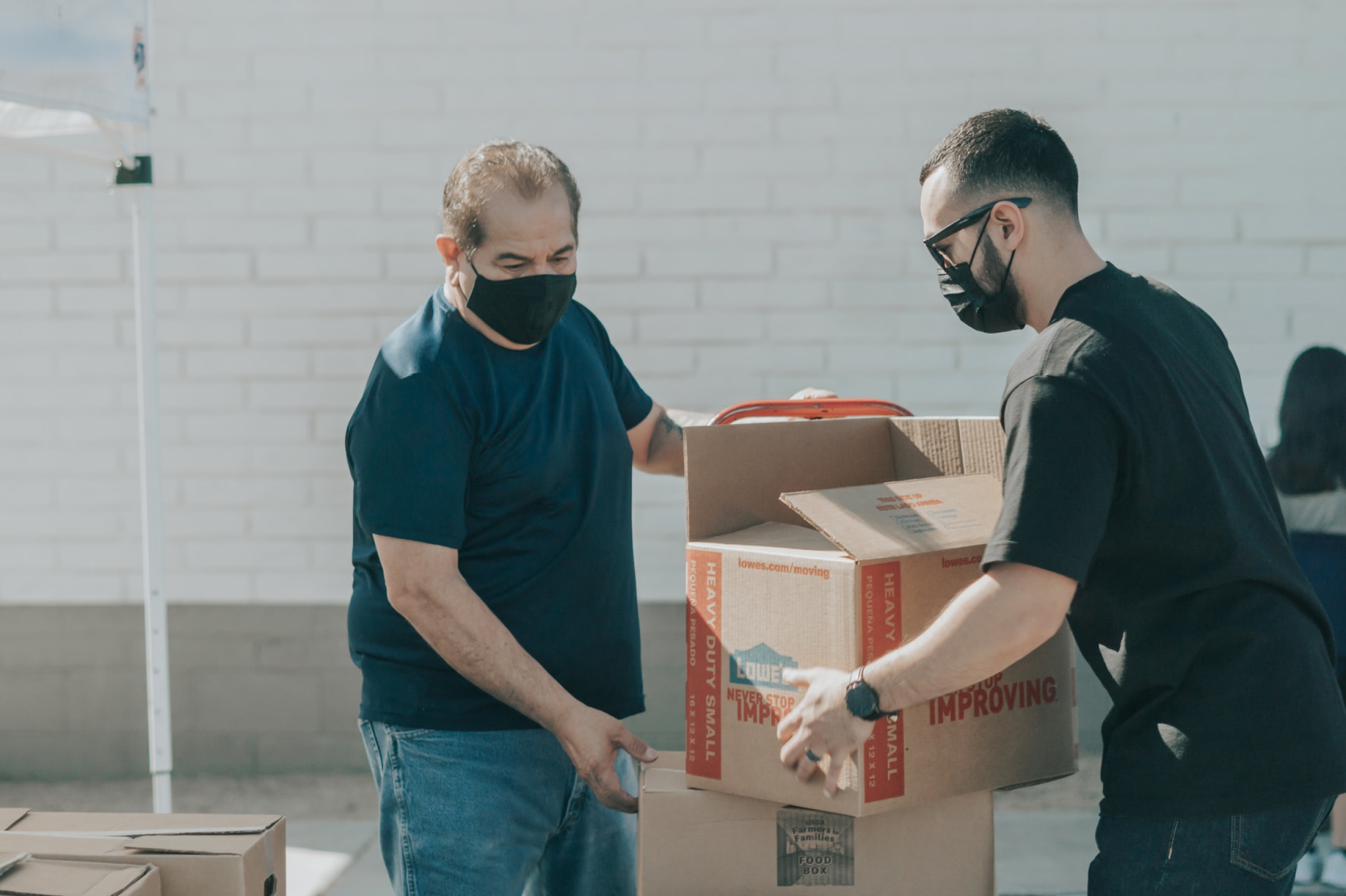 Two men working together to lift boxes.